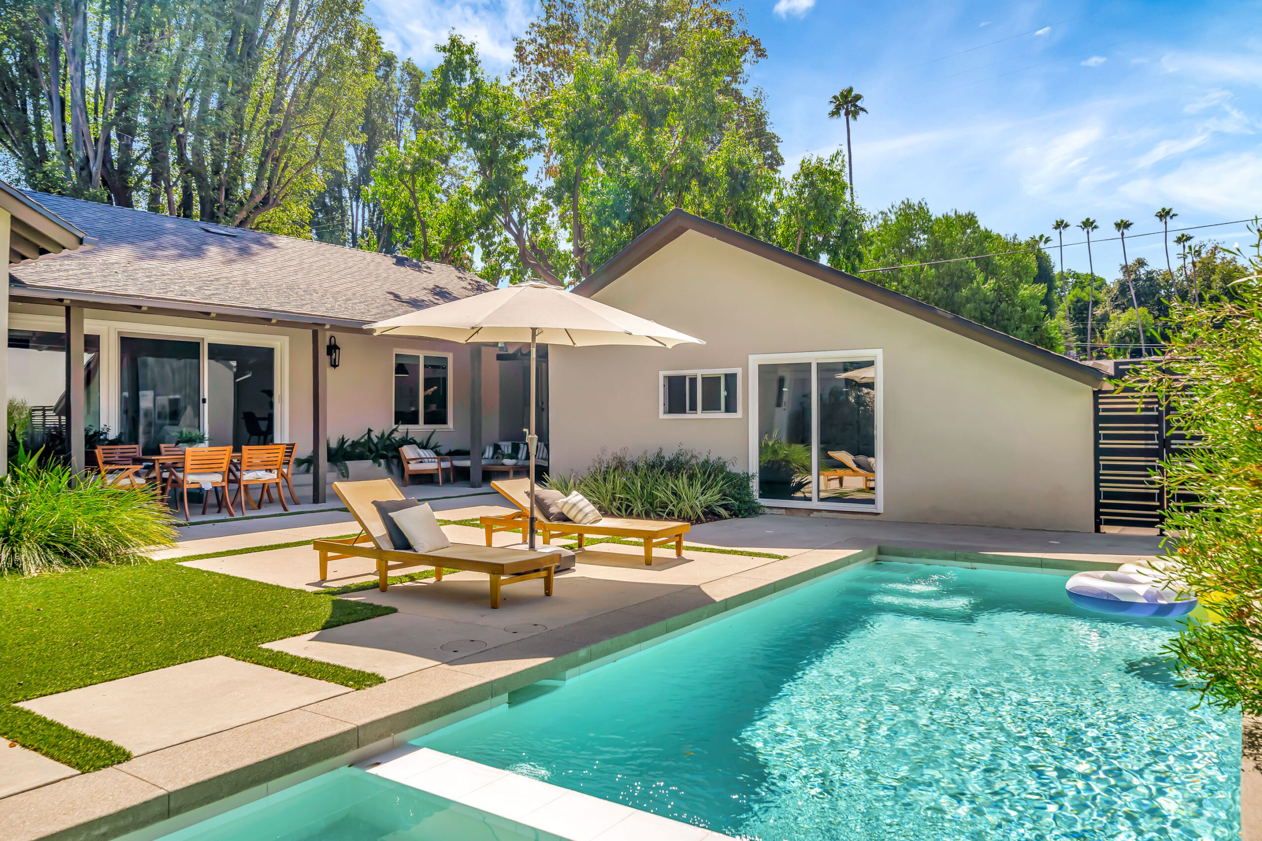 Backyard poolside with loungers, umbrella, and outdoor seating